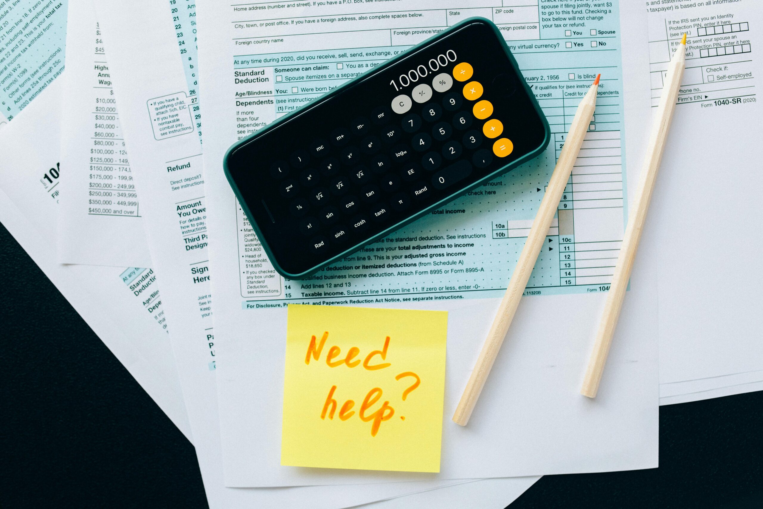 A calculator and tax forms with pencils nearby, symbolizing the efficiency of outsource bookkeeping solutions for small businesses.